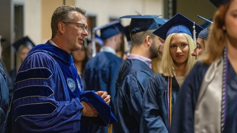 Penn State Behrend Chancellor Ralph Ford talks with students prior to the college's spring 2022 commencement program.