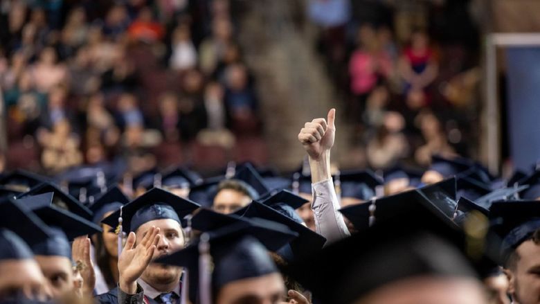 A new graduate gives the thumbs-up sign during Penn State Behrend's spring 2022 commencement ceremony.