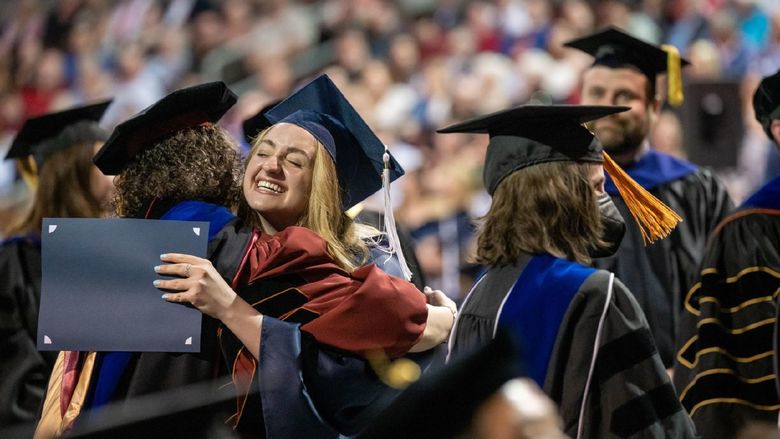 A student hugs a faculty member at Penn State Behrend's spring 2022 commencement program.