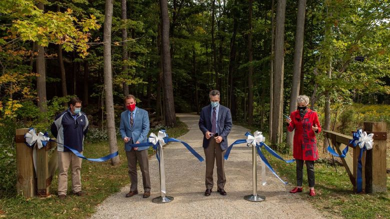 Four guests cut a dedication ribbon on a trail in Penn State Behrend's Wintergreen Gorge.