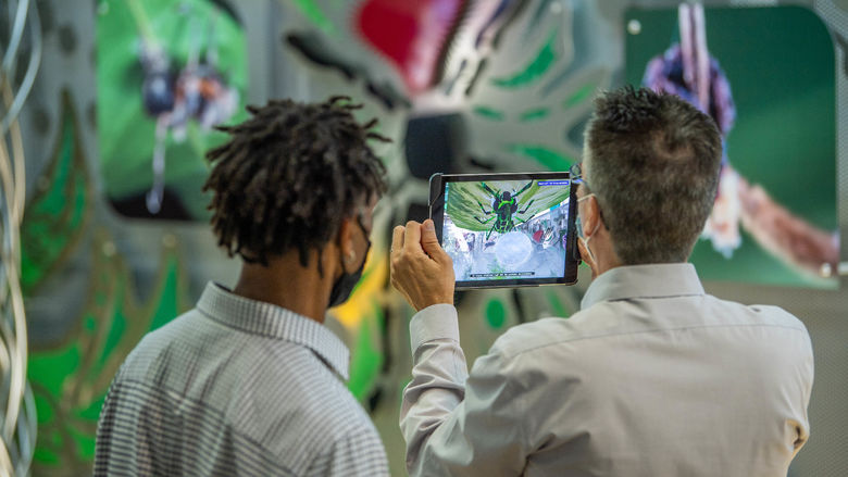 Two men use an iPad to explore an interactive art sculpture that incorporates augmented reality.