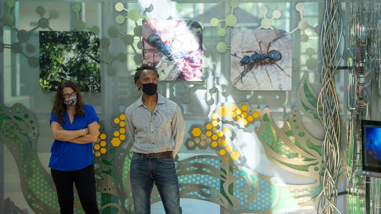 A woman and a man stand in front of an interactive art sculpture at Penn State Behrend.