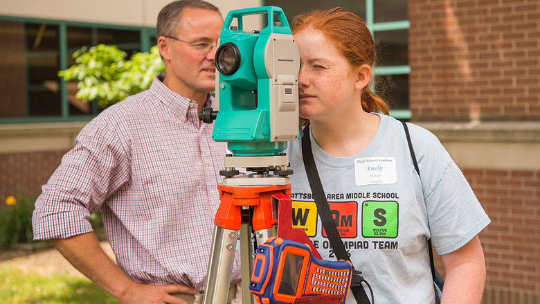 Professor shows student how to use surveying and data collection equipment.