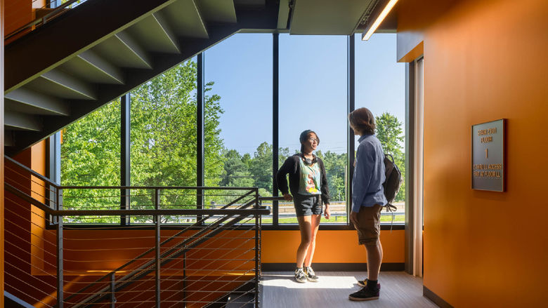 Two students talk on a stairway landing in Penn State Behrend's Federal House.