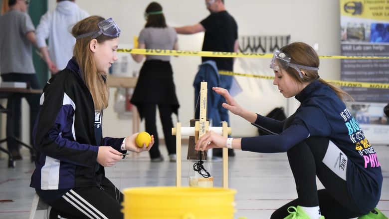 Two girls adjust a model trebuchet at the regional Science Olympiad at Penn State Behrend.