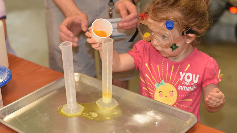 A preschooler works on a science experiment during Preschool Science Story Time.