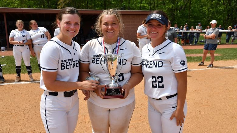 Three Penn State Behrend softball players hold the AMCC runner-up trophy.