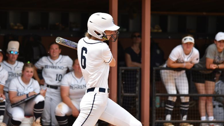 A Penn State Behrend softball player swings at a pitch.