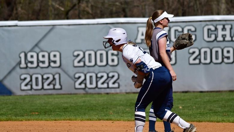 A Penn State Behrend softball player cheers while standing on base.