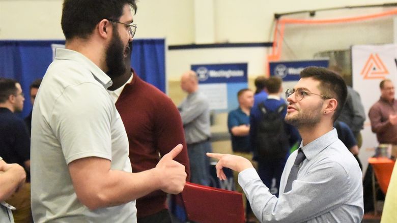 A student gestures while talking with a recruiter at Penn State Behrend's spring Career and Internship Fair.