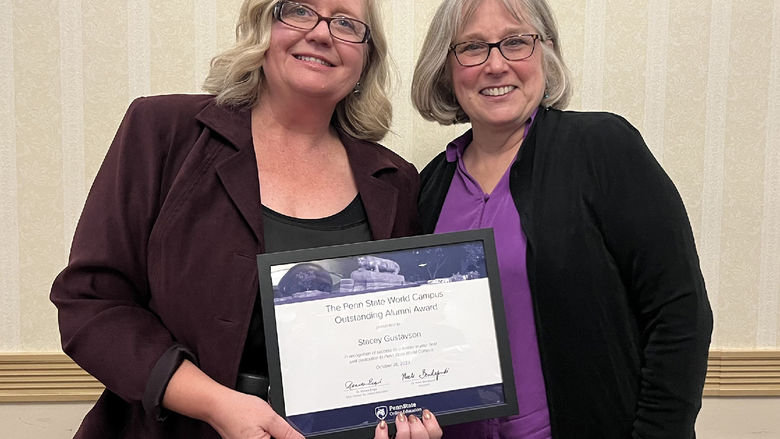 Stacey Gustavson, hold a framed award, stands next to her professor