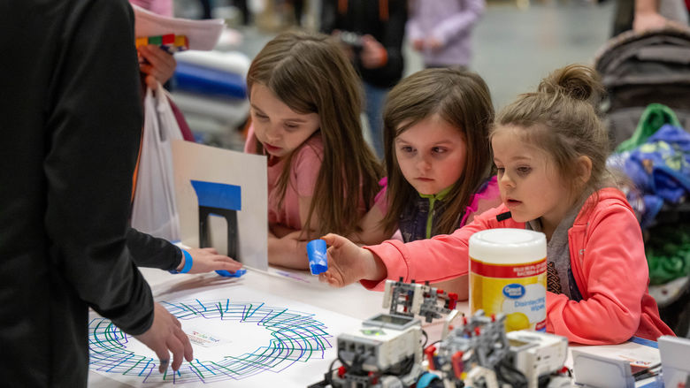 Three girls experiment with a robotic pen at Penn State Behrend's annual STEAM Fair.