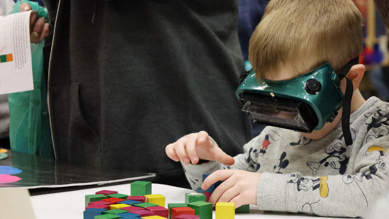 A young boy stacks blocks while wearing VR/AR goggles