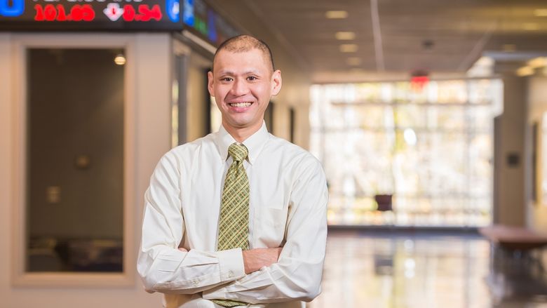 A Penn State Behrend faculty member stands outside the financial trading lab in Burke Center.