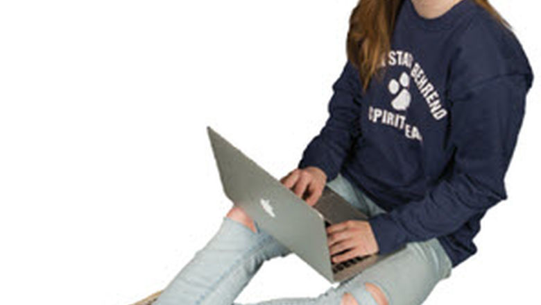 Female student sitting with laptop resting on her lap