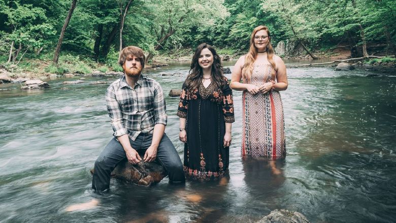 Members of the band The Barefoot Movement pose while wading in a river.