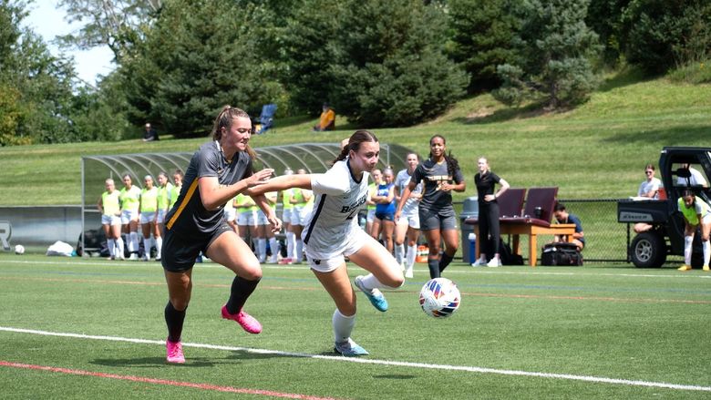 A Penn State Behrend women's soccer player runs past a defender.