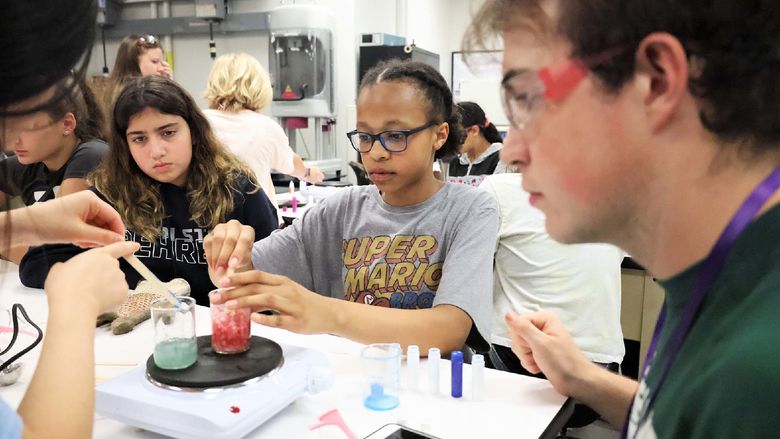 Several youth work with colored fluids in a lab at Penn State Behrend