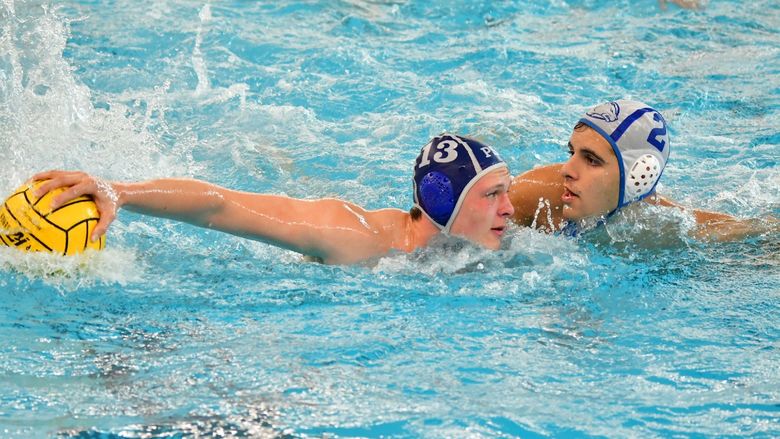Two water polo players face each other in the pool.