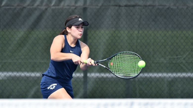 A Penn State Behrend tennis player hits a backhand.