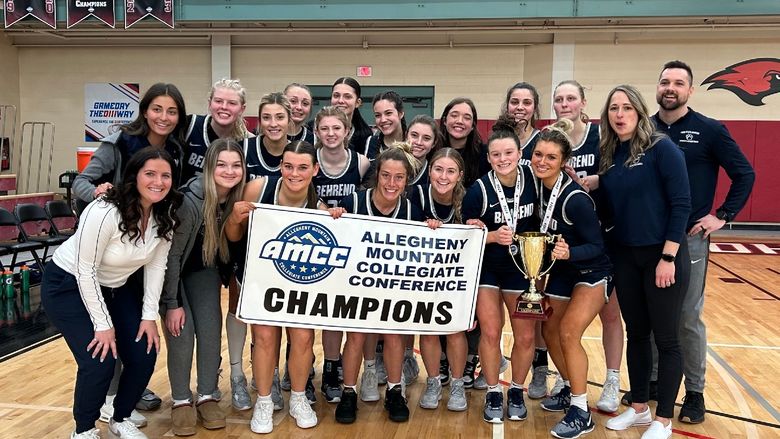 The Penn State Behrend women's basketball team holds the AMCC championship banner.