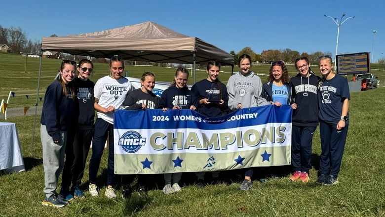 The Penn State Behrend women's cross country team poses with the AMCC championship banner.