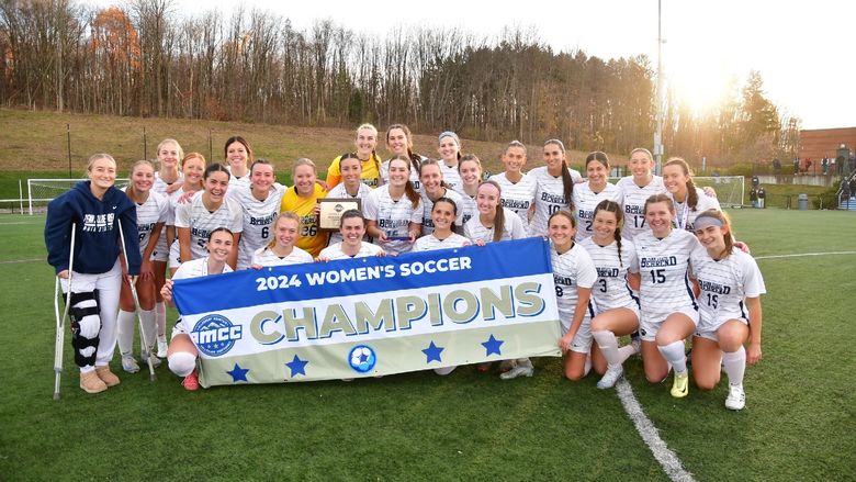 The Penn State Behrend women's soccer team poses with the AMCC championship banner.