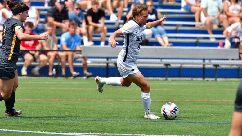 A female Penn State Behrend soccer player advances with the ball.
