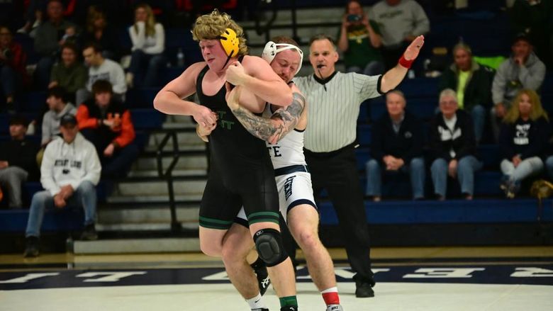 A Penn State Behrend wrestler grabs an opponent from  behind while standing.