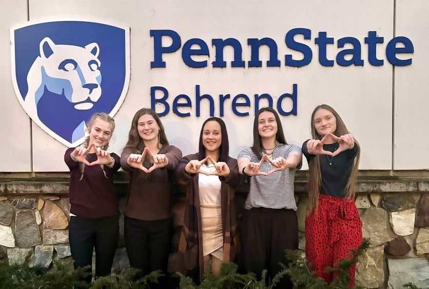 Five female students hold their hands up in the symbol for the Four Diamonds Fund.