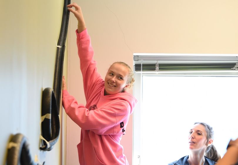 A middle-school student reaches up to place a marble in a model roller coaster track.