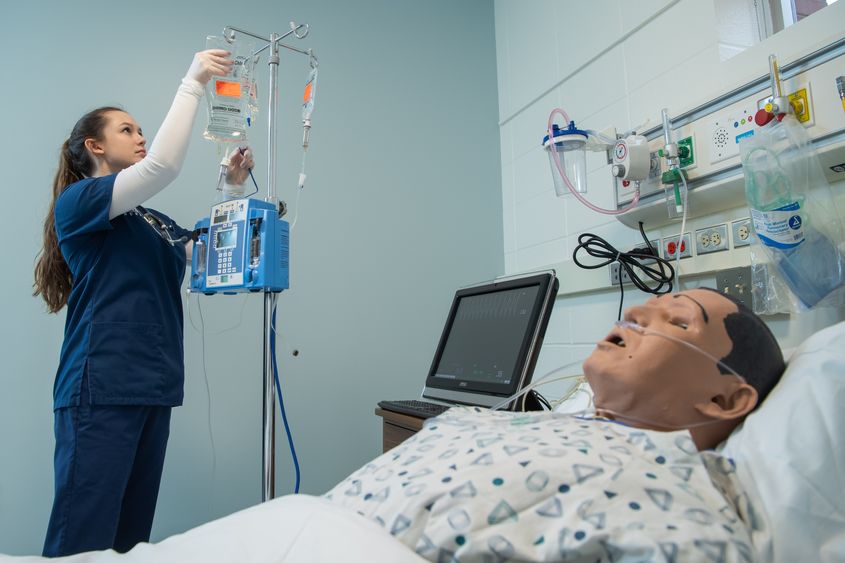 A nursing student prepares an IV in Penn State Behrend's nursing simulation lab