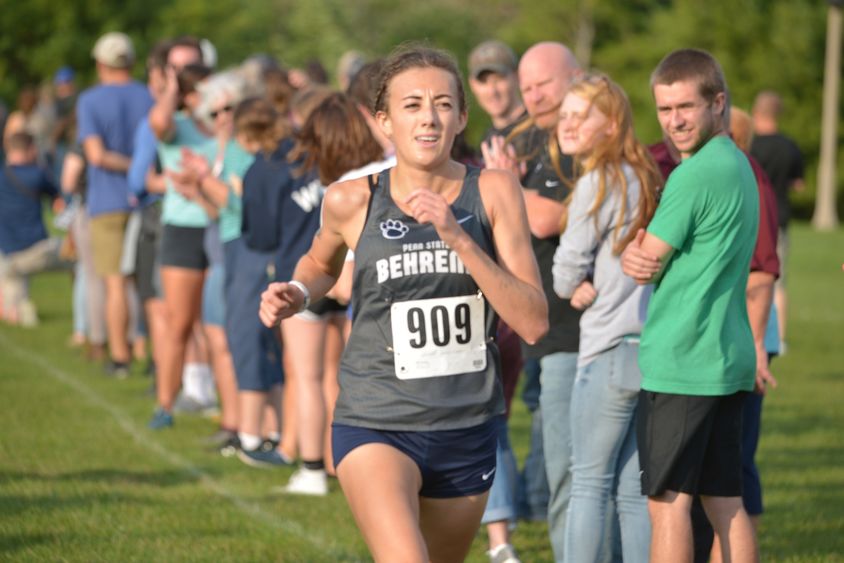 A female Penn State Behrend runner competes in a cross country race.