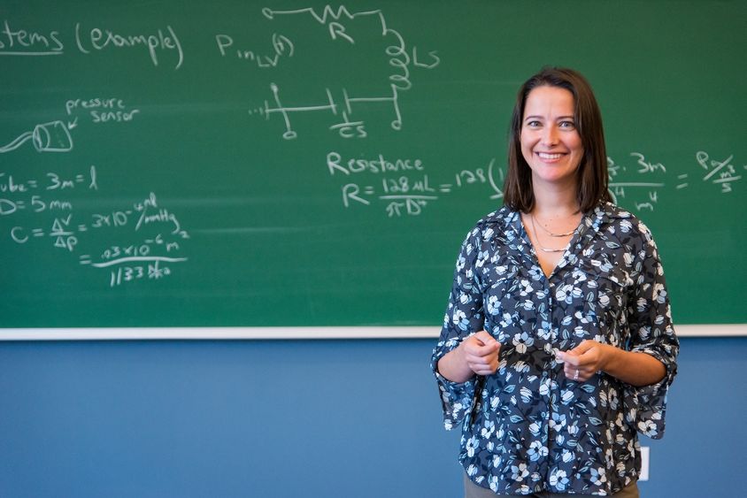 A professor stands at a chalkboard.