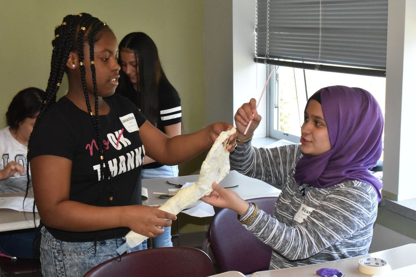 Lanaziana Glover, left, and Weam Kathen, both seventh-grade students at East Middle School, work on building a tennis racket during the "Tennis Anyone?" activity at Math Options Career Day. 