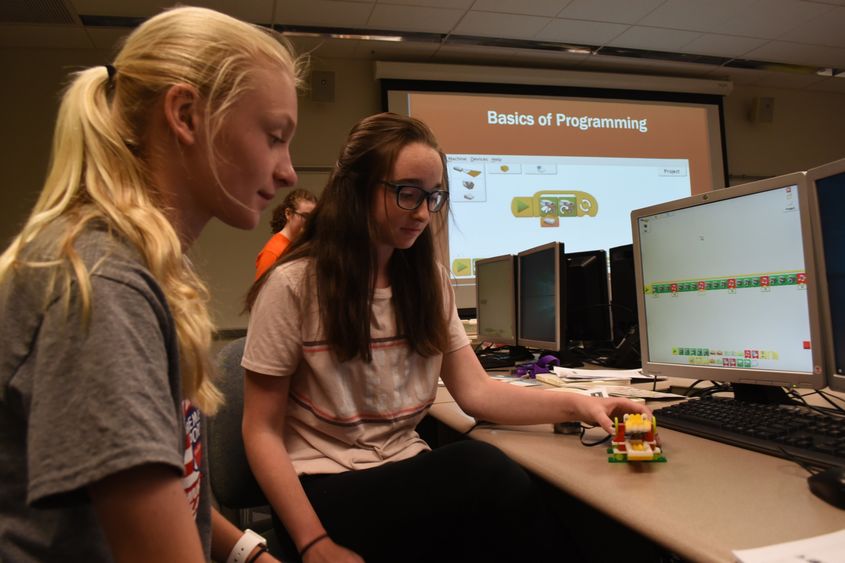 Sydney Rotko, at left, and Sammy Fellows, both students in the General McLane School District, work on programming the alligator they created as part of GE Girls @ Penn State Behrend.