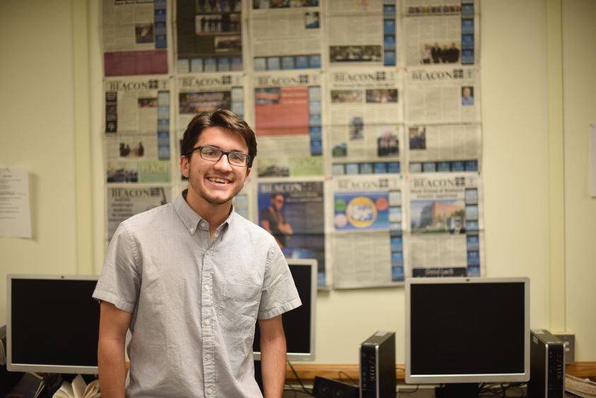 Josh Kolarac stands in front of a display of Behrend Beacon newspapers.