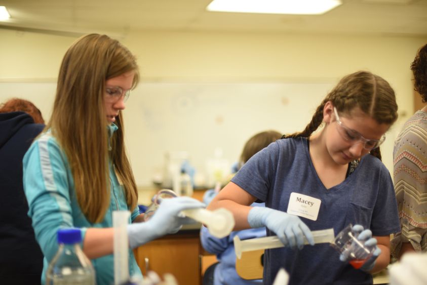 Abbey Frederick and Macey Eyler pour DNA into beakers.