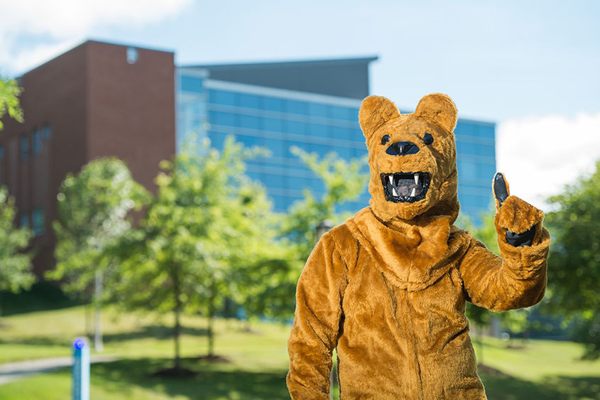 The Penn State Nittany Lion mascot poses in front of Burke Center at Penn State Behrend