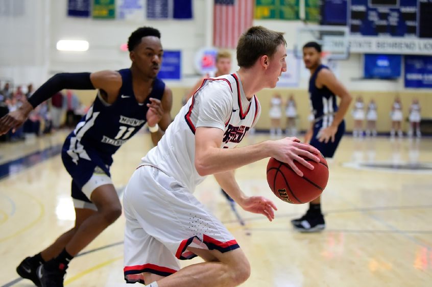 A Penn State Behrend basketball player dribbles toward the net.