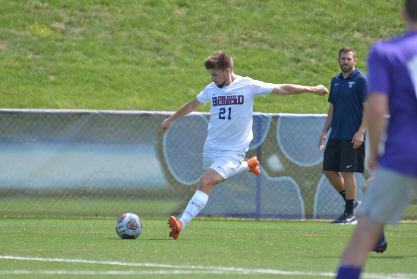 A Penn State Behrend soccer player kicks the ball upfield.