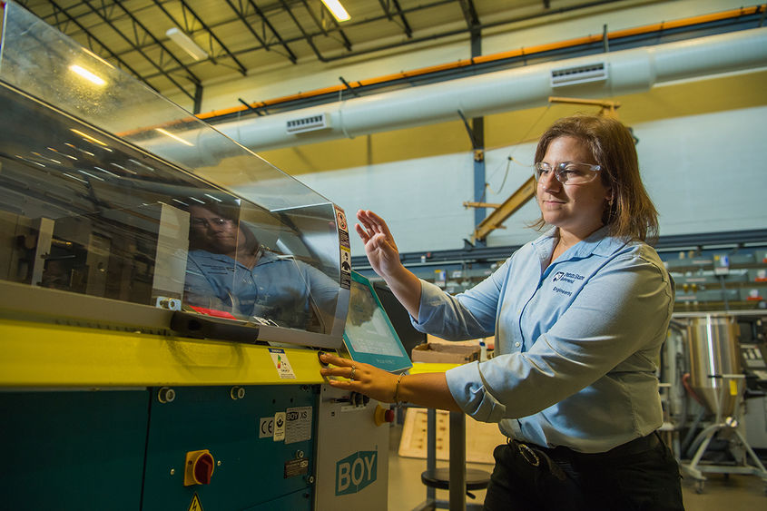 Woman operating plastics processing equipment