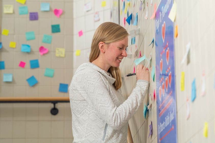 Penn State Behrend alumna Ashlyn Kelly writes on a sticky note in a stairwell of the Reed Union Building at Penn State Behrend.