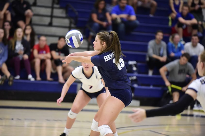A Penn State Behrend volleyball player digs the ball during a match.