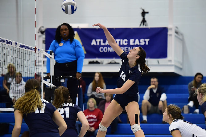 A Penn State Behrend women's volleyball player spikes the ball.