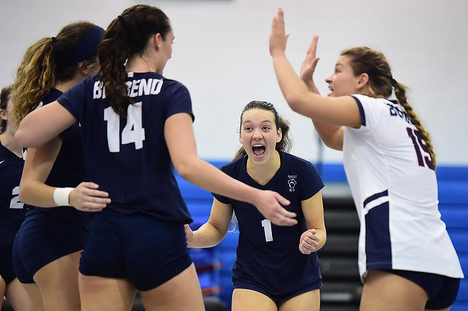 Penn State Behrend volleyball players celebrate after scoring a point.