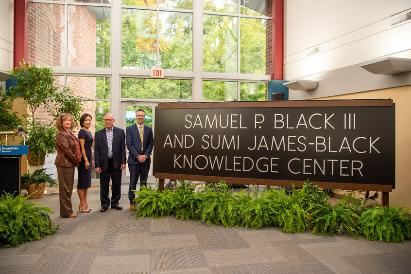 Four officials stand near the new sign for the Samuel P. Black III and Sumi James-Black Knowledge Center