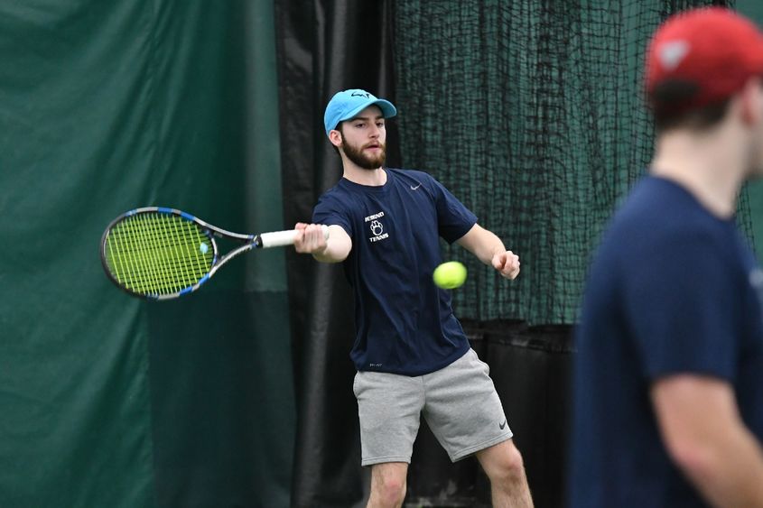 A Penn State Behrend tennis player hits a forehand shot.