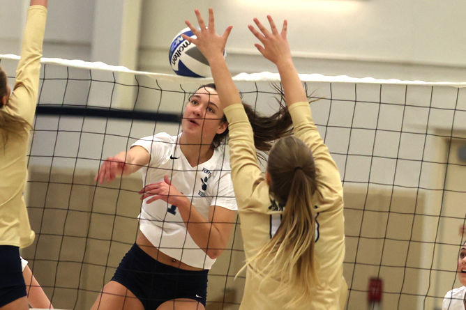 A Penn State Behrend volleyball player spikes the ball.