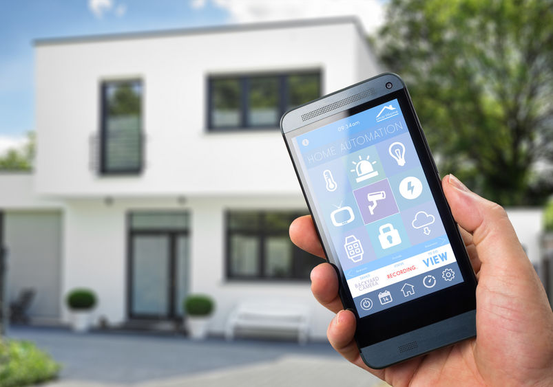 A stock photo of a man holding a smartphone in front of a house.